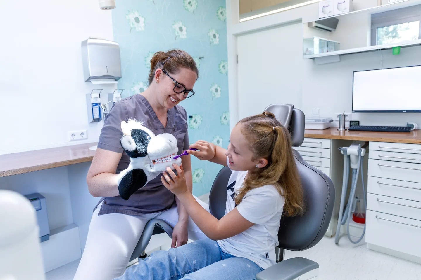 Kinderzahnheilkunde in Bühl – ein Kind übt das Zähneputzen an der Kuh-Handpuppe